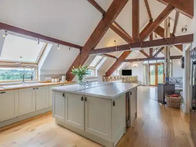 a large kitchen with white cabinets and a large island at Bedw Barn in Newtown