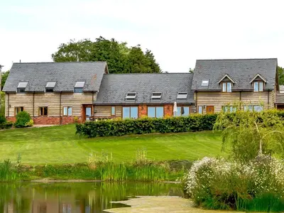 a large house on a hill next to a lake at Bedw Barn in Newtown