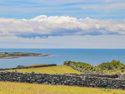 a stone wall on a hill next to the ocean at Bramble Bank in Harlech