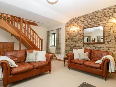 two brown leather couches in a living room with a stone wall at Bullfinch Cottage in Leominster