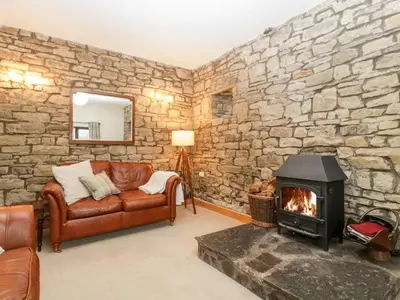 a living room with a stone wall with a fireplace at Bullfinch Cottage in Leominster