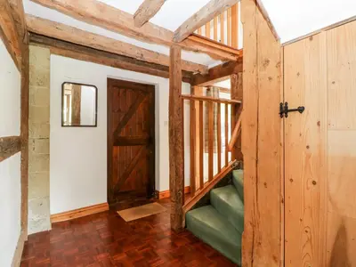 a room with a wooden door and a green couch at Redstart Cottage in Leominster