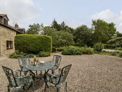 a table and chairs sitting on a gravel patio at Redstart Cottage in Leominster