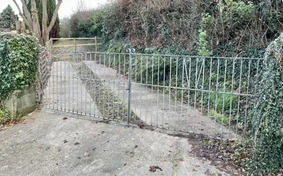 a metal gate in front of a garden at Taylor Way - Superb Apartment with Living Room and Private Gated Parking in Aberystwyth