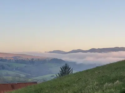 a hillside with a view of a foggy valley at Summerhill Tanyrhos in Blaenau-Ffestiniog