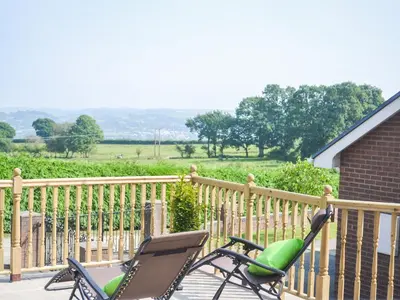 a rocking chair on a porch with a fence at Gwynfan Bungalow in Llandrindod Wells