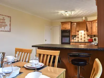 a kitchen with a table with chairs and a counter top at Gwynfan Bungalow in Llandrindod Wells