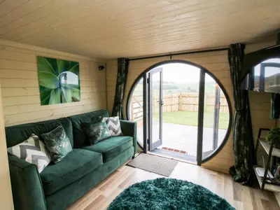 a living room with a green couch and a large window at Callow Pod in Shrewsbury