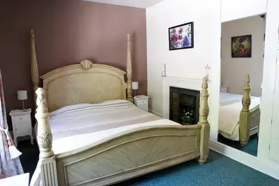 a bedroom with a large bed and a fireplace at Country Mansion - Private Annexe in Llanwrda