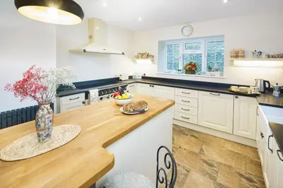 a kitchen with white cabinets and a wooden counter top at Ty Bledrws - family retreat near the Cardigan Bay coast in Llangybi