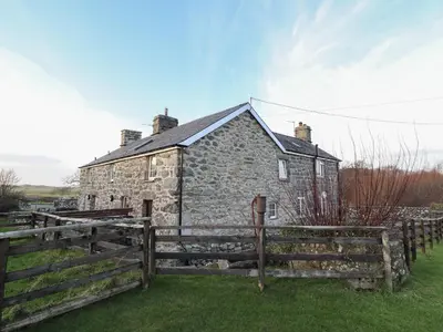 an old stone house with a fence in front of it at Ynys in Dyffryn