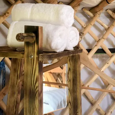 a pile of towels on top of a wooden stand at 'Villager' the Yurt at Pentref Luxury Camping in Penuwch