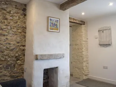 a fireplace in a room with a stone wall at Tan Y Llidiart in Llangedwyn