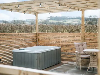 a hot tub sitting on a patio under a pergola at Swallow Lodge - Uk42540 in Winforton