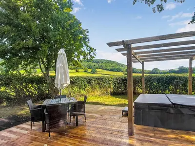 a wooden deck with a table and chairs and an umbrella at Cuckoo Lodge - Uk42541 in Winforton