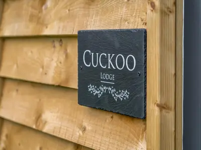 a black sign on the side of a wooden wall at Cuckoo Lodge - Uk42541 in Winforton