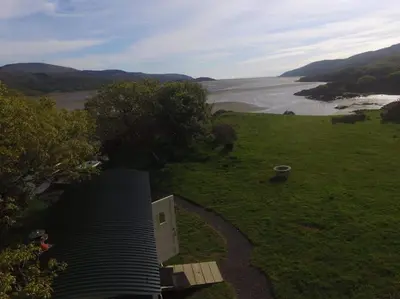 a house in a field with a view of a river at Snowdonia Shepherds Hut + Hot Tub in Barmouth