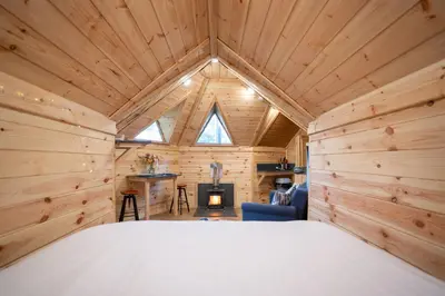 a bedroom in a log cabin with a bed and a fireplace at Chestnut Tree House with Hot tub & Sauna in Barmouth