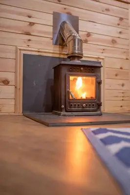 a woodburning stove in a wooden room with a stove at Pine Tree House with Hot tub & Sauna in Barmouth