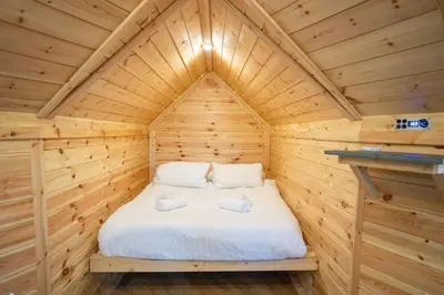 a bed in a wooden cabin with two towels at Pine Tree House with Hot tub & Sauna in Barmouth
