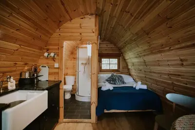 a bathroom with a bed in a wooden cabin at Snowdonia Mawddach Cabin and hot tub Glamping in Barmouth