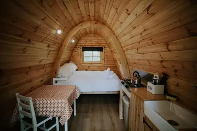 a bedroom in a log cabin with a bed and a sink at Willow Cabin & Hot Tub in Barmouth