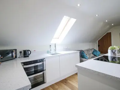 a white kitchen with a sink and a stove at Stable Cottage in Bishops Castle