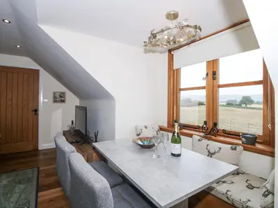 a dining room with a table and chairs and a window at Stable Cottage in Bishops Castle