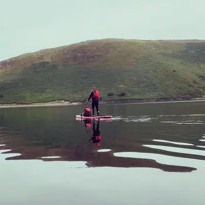 a woman standing on a paddle board in the water at Geodesic Dome Glamping in Llanidloes
