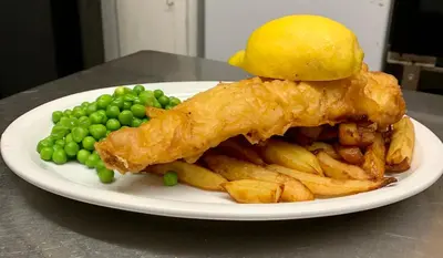 a plate of food with fish and french fries and peas at The Slaters Arms Corris in Machynlleth