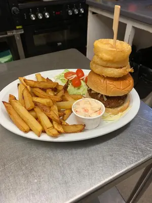 a plate with a hamburger and french fries on a table at The Slaters Arms Corris in Machynlleth
