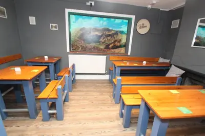 a dining room with wooden tables and a painting on the wall at The Slaters Arms Corris in Machynlleth