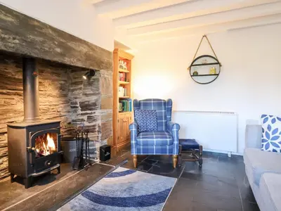 a living room with a fireplace and a blue chair at Ael Y Bryn in Blaenau-Ffestiniog