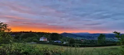 a house on a hill with a sunset in the background at Odli Glamping - Aderyn in Welshpool