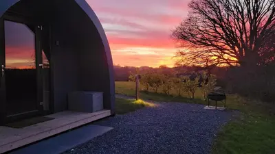 a building with a sunset in the background at Odli Glamping - Aderyn in Welshpool
