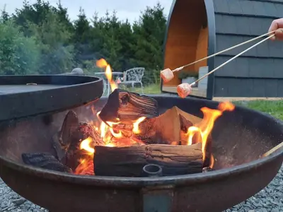 a person is cooking food in a fire pit at Odli Glamping - Aderyn in Welshpool