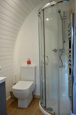 a bathroom with a toilet and a shower at Eastridge Glamping Pods in Shrewsbury