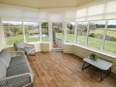 a living room with a couch and chairs and windows at The Marshes in Welshpool