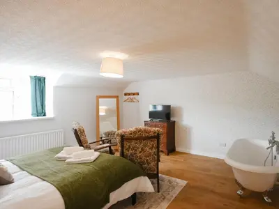 a bedroom with a bed and a tub and a sink at Dolwen Isaf in Llangadfan