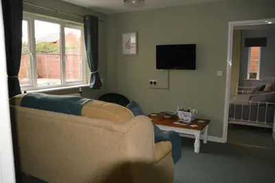a living room with a couch and a tv at The Coach House at Copper Hall in Leominster
