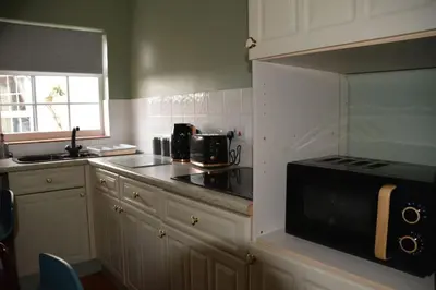 a kitchen with white cabinets and a black stove at The Coach House at Copper Hall in Leominster