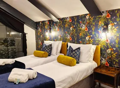 two beds in a room with a floral wall at The Academy House by Bevolve in Shrewsbury