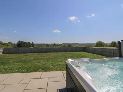 a hot tub on a patio with a yard at Elan Valley Welsh - The Sheepfold in Llandrindod Wells