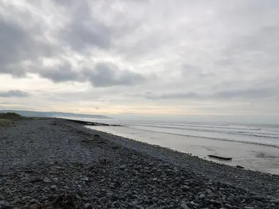a beach with rocks and the ocean on a cloudy day at Gwent 74 in Borth