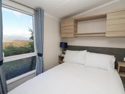 a bedroom with a bed and a large window at Gwent 74 in Borth