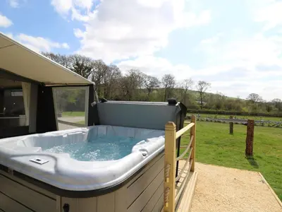 a hot tub sitting on a patio next to a field at Otter in Nantmel