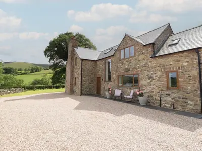 an external view of a stone house with two chairs at Cwmwr in Pen-y-bont-fawr