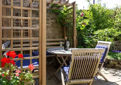 a patio with a table and chairs in a garden at Corve Cottage Historic cottage in beautiful ludlow in Ludlow