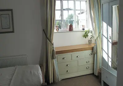 a bedroom with a bed and a dresser with a window at Corve Cottage Historic cottage in beautiful ludlow in Ludlow