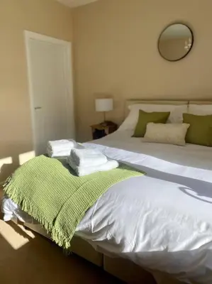 a bedroom with a bed with a green blanket on it at A spacious hidden gem with hot tub, lovely garden & views in Kington
